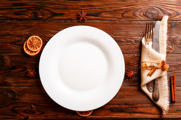 Christmas table setting concept. Fork and knife, slices of dried orange on brown wooden table....