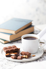 Cup of coffee, chocolate and books on a light background. Home study or freelance concept
