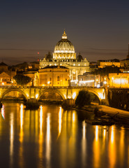 Fototapeta na wymiar Illuminated St. Peter's Basilica and reflections in the Tiber River after sunset in Rome, Italy