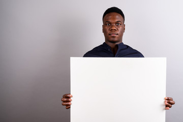 Young African businessman holding white board against white back