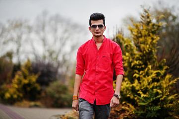 Obraz premium Indian man at red shirt and sunglasses posed outdoor.