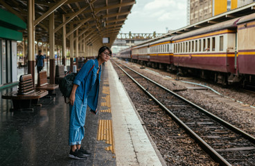 Fototapeta na wymiar Asian woman traveler waiting train on the platform of the railway station- travel and transportation concept