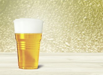 Plastic glass with beer on table