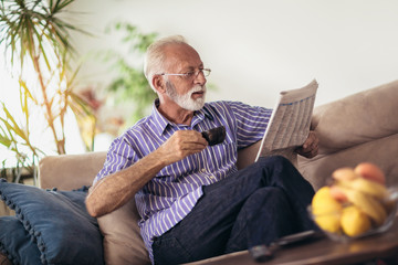 Senior man at home reading newspaper