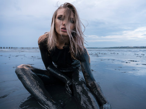 Portrait of Blonde Caucasian Girl Crawls Smeared in a Healthy Black Mud in old Firth