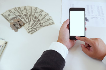 High-angle of man using smartphone in office with money on working desk.