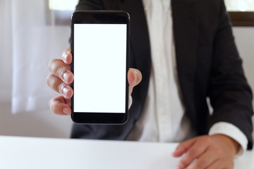 Businessman holding smartphone forward empty white screen for your text or picture.