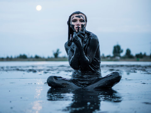 Portrait of an Adorable Caucasian Girl Sitting and posing Smeared with a Healthy Black Mud in old Firth