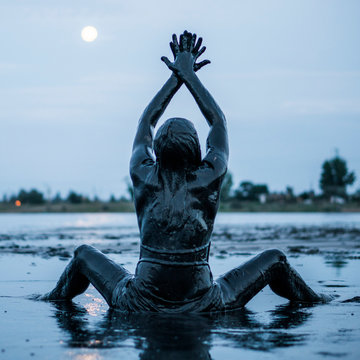 Portrait of an Adorable Caucasian Girl Sitting and posing Smeared with a Healthy Black Mud in old Firth