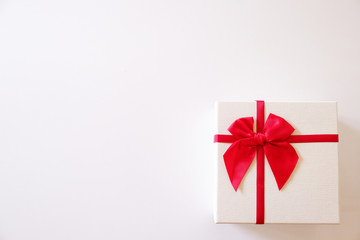 Close-up  white gift box with red ribbon on white background.