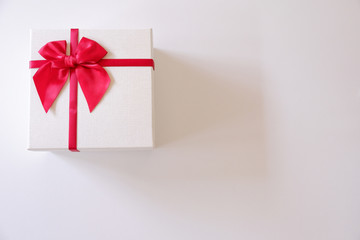 Close-up  white gift box with red ribbon on white background.