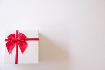 Close-up  white gift box with red ribbon on white background.