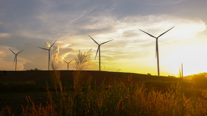 Wind turbines produce electricity and sunlight during sunset.