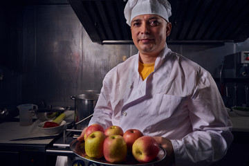 Chef cook in a white apron and cooks hat on a kitchen