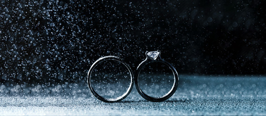 Two wedding rings in infinity sign with sparkling light mist. Love concept on black background....