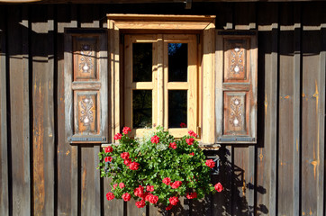 Fototapeta na wymiar Old wooden traditional window with red flower