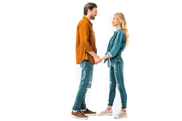 side view of young couple holding hands and looking at each other isolated on white