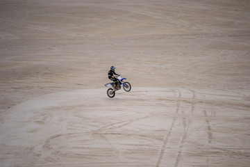 Playing with the motorbike in the dunes desertic place