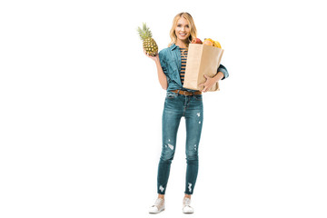young woman holding pineapple and paper bag with products isolated on white