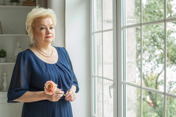 Portrait of beautiful older woman with rose flower at home