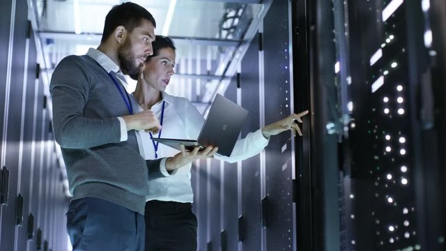 Looped Cinemagraph: Male and Female IT Engineers Standing in the Working Data Center with Server Racks LED Lights Blinking.