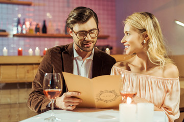 happy young couple looking at menu during romantic dinner in restaurant