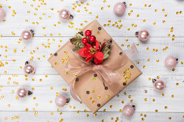 Christmas presents and gift boxes wrapped in kraft paper on a wooden table with gold glitter and pink balls, fir-tree branches, and decoration, top view. Flat lay, copy space for text.