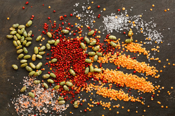 Dried lentils and soya beans  with red peppercorns and rock salt scattered on slate natural background