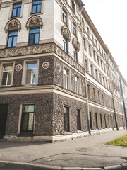 The facade of the historic old building with sculptures is against the background of blue clear sky in St. Petersburg, the sun shines