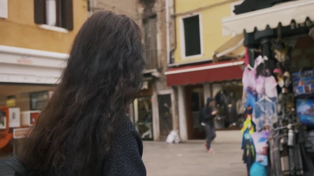 Attractive girl walking through the narrow streets of Venice, Italy. Travel tourist multiracial woman with backpack in casual clothes enjoying traveling outdoors during holidays in Europe. Slow motion