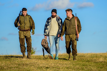 Group men hunters or gamekeepers nature background blue sky. Guys gathered for hunting. Men carry hunting rifles. Hunting as hobby and leisure. Hunters with guns walk sunny fall day. Brutal hobby