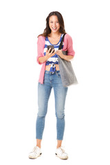 Naklejka premium trendy young asian woman standing against isolated white background with purse and mobile phone