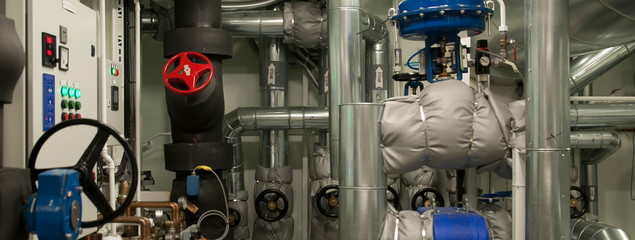 Equipment, cables, pipes and valves in engine room of a ship power plant