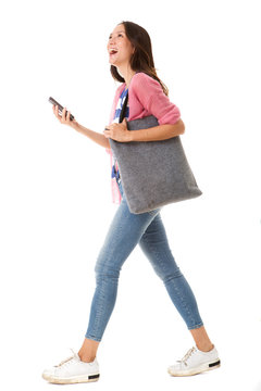 side portrait of fashionable young asian woman walking with purse and smart phone against isolated white background