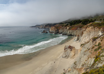 Fototapeta na wymiar Big Sur California coast, bridge, beach, rocks, clouds, and surfing waves