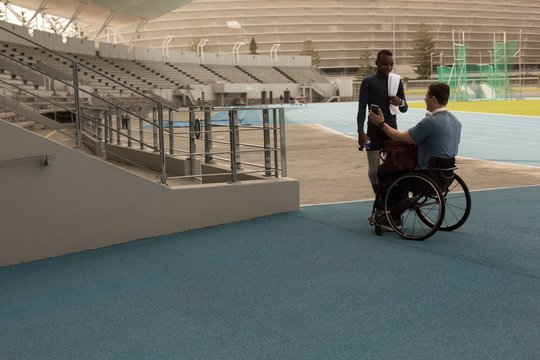 Two disabled athletes talking over mobile phone in stadium