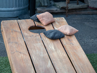 Competing black and beige beanbags sitting on cornhole platform