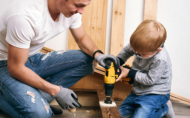 Family time: Dad shows his son hand tools, a yellow screwdriver and a hacksaw. They need to drill...