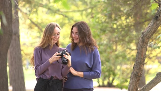 Girls in park.
Girls stand in park and check pictures in photo camera. They enjoy the photosetion and laugh. Positive mood. Student's live.