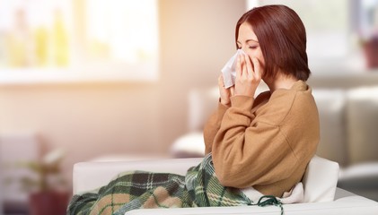 Brunette woman sneezing in a tissue in the living room