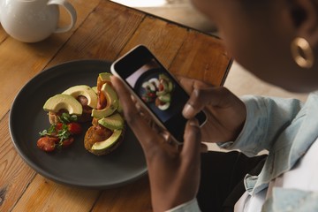 Close up of woman taking picture of food in cafe