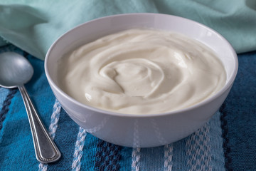 Greek yogurt in bowl close up on blue table cloth - Natural yoghurt background