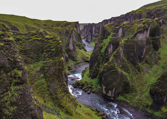 The Fjadra river flows through Fjadrargljufur Canyon: black rocks covered with soft green moss. Stunning summer view of Iceland, Europe. 