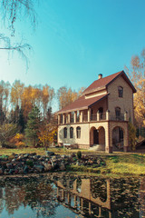 Fototapeta na wymiar Beautiful Cottage with garden and pond in the autumn forest.