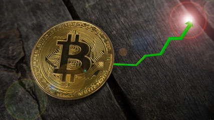 Bitcoin coin put on the wooden table have a graph is up green arrow . Concept Up trend of digital money.