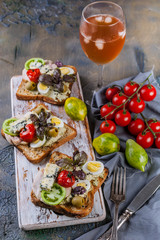 Appetizing toasts with avocado, quail eggs, tomatoes, Dor Blue cheese and a glass of cold white wine. Author's cuisine. Original serving dishes