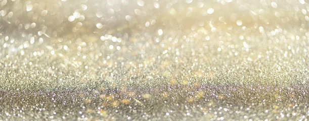 Gold and silver abstract bokeh lights. Shiny glitter background with copy space. New year and Christmas concept. Sparkling greeting card. Banner.