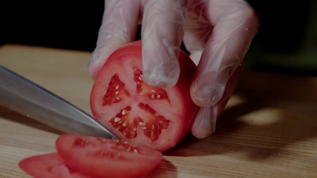 Chef making burger. Closeup mans hands cutting tomato for hamburger.