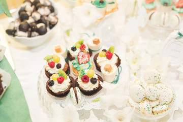 Delicious sweets on wedding candy buffet with desserts, cupcakes