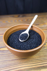 Black cumin (nigella sativa or kalonji) seeds in spoon on wooden background, selective focus